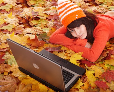 Girl in autumn orange leaves with laptop.Fall sale.