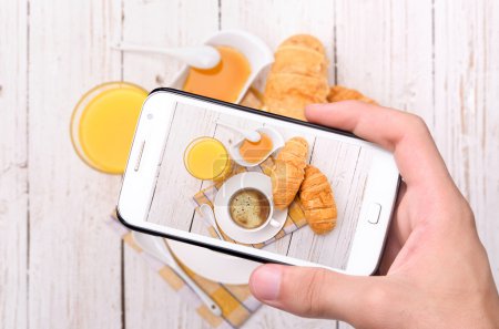 Hands taking photo breakfast with smartphone