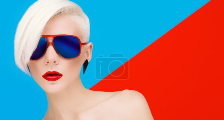 Fashion blond woman with trendy hairstyle and sunglasses on a bl