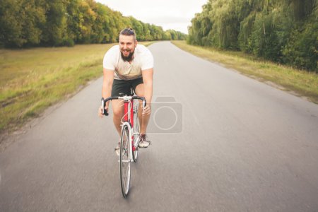 Young bearded hipster driving bicycle