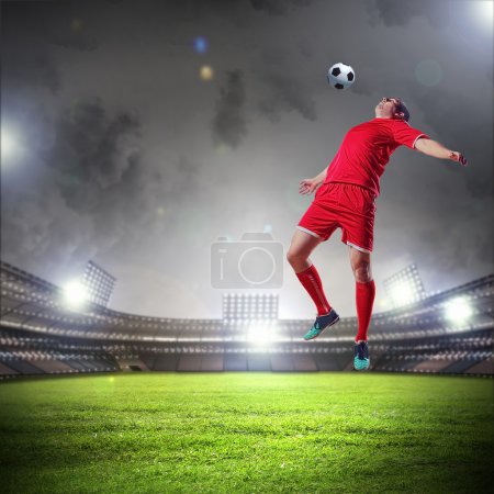 Football player in red shirt striking the ball at the stadium