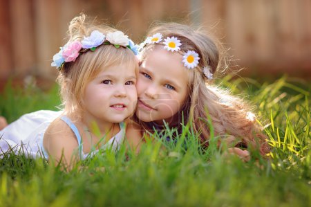 portrait of two happy little sisters on green grass