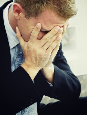 Distraught sad business man with hands in face