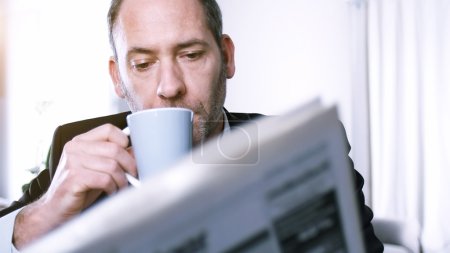 businessman reading newspapers and drinking coffee
