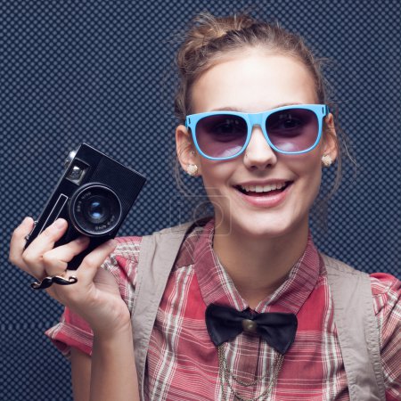 Portrait of beautiful hipster style young woman in white shirt and bow-tie. Old camera hanging by the neck