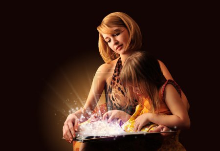 Young mother and her little daughter reading fairy book
