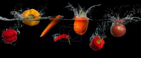 Vegetables in the water splash over black background. Healthy food and active life.