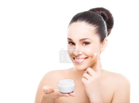 Smiling woman applying cosmetic cream