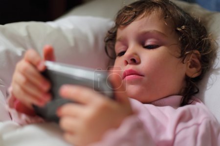 Little girl in bed with hendheld computer