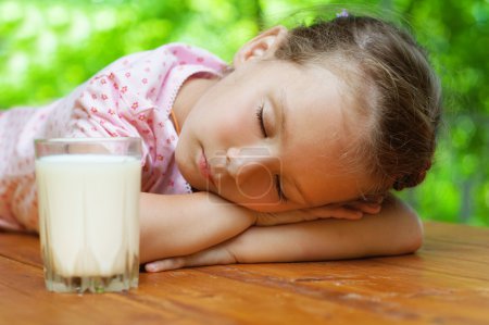 Little girl sleeps around glass of milk