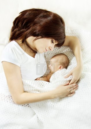 Mother embracing sleeping newborn baby