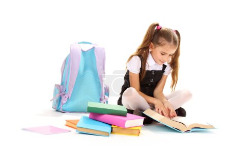 Beautiful little girl, books and a backpack isolated on white