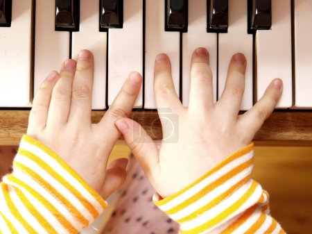 Close up of child's hands playing the piano