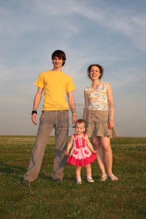 Family with baby on evening meadow