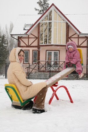 Mother with baby on winter seesaw