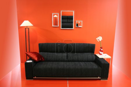 Black sofa on red wall