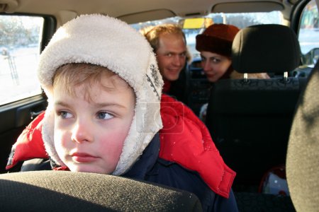 Sad boy in winter family car