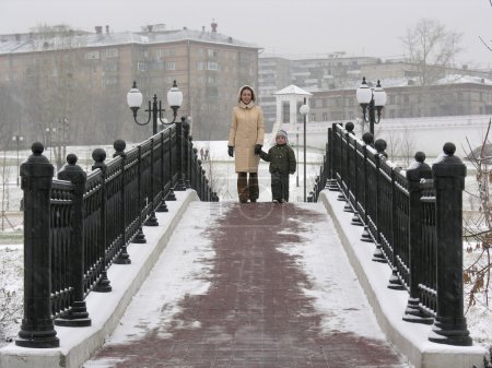 Mother with son on winter bridge