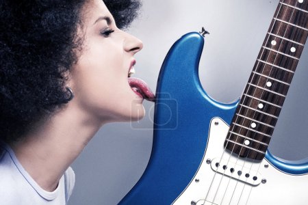 Beautiful rock-n-roll girl licking a guitar
