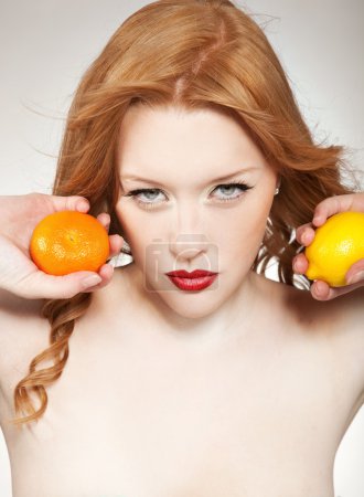Young woman holding orange an lemon