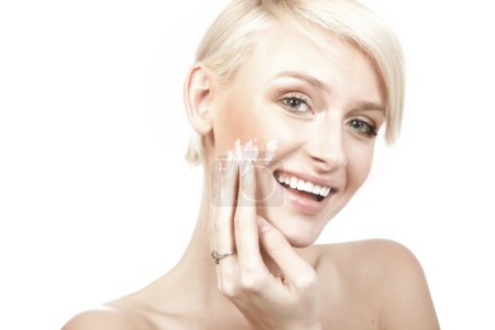 Calm beauty portrait of a smiling young woman putting cream