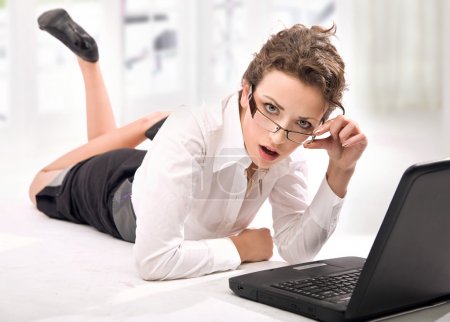 Happy young businesswoman with laptop on the floor