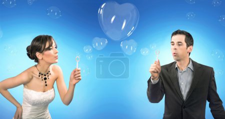Wedding couple blowing heart shaped romantic soap bubbles