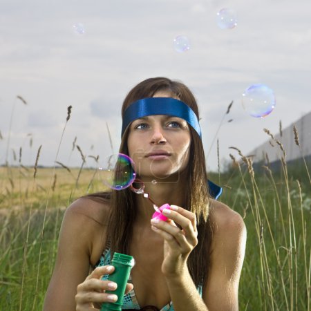 Thoughtful woman blowing soap bubbles