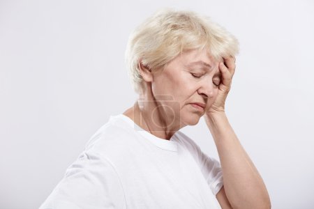 An elderly woman rests her head on a white background