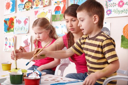 Children painting with teacher in art class.