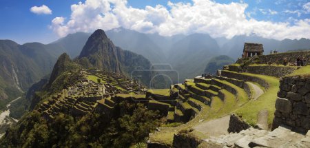 Panoramana of Machu Picchu, Guard house, agriculture terraces, Wayna Picchu and surrounding mountains in the background.