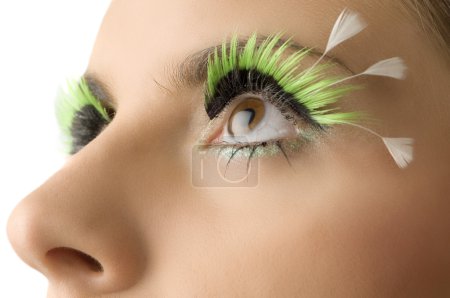 close up on the eyes of a young woman with artificial green eyelashes
