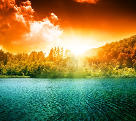 Green water lake in forest and sunset