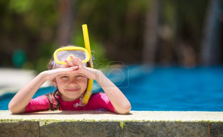 Adorable little girls at mask and goggles in outdoor swimming pool