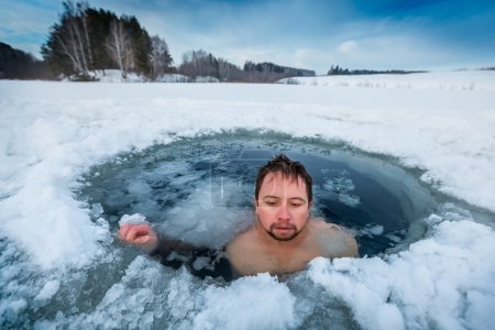 Young man swimming in the winter lake