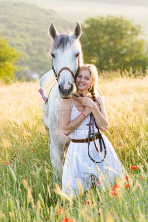 Young woman standing with a white horse outdoor