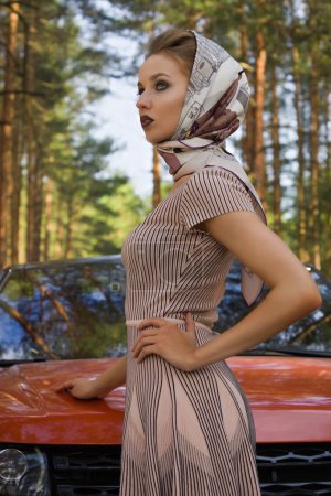 Lady in vintage dress standing near car