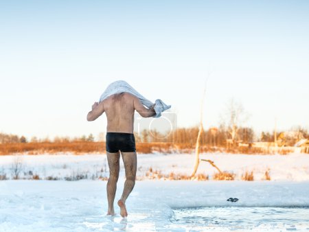 man wipes towel after swimming in  freezing hole