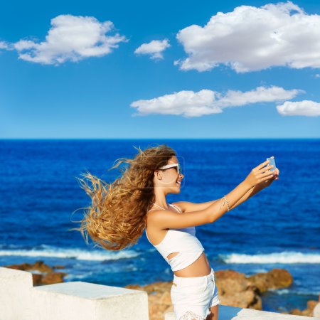 Blond teen girl photo selfie on smartphone at beach