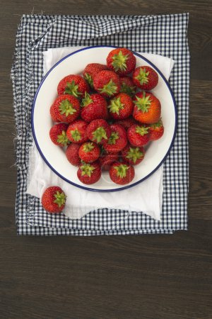Fresh juicy strawberries on vintage enamelware crockery on rusti