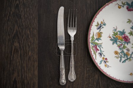 Vintage plate and vintage cutlery on rustic dark wooden backgroun