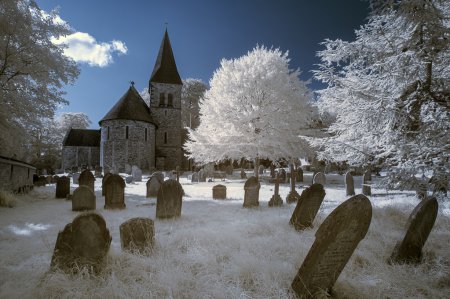 Infrared landscape of old church in churchyard in English countr