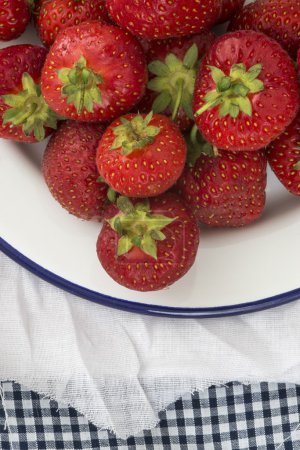 Fresh juicy strawberries on vintage enamelware crockery on rusti