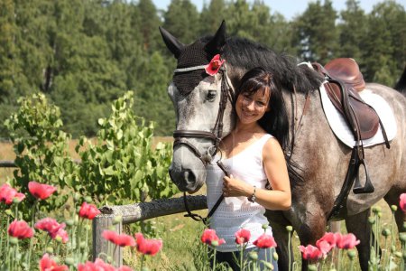 Beautiful woman in the blooming garden with horse