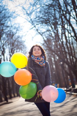 Beautiful woman with colorful balloons in the spring park
