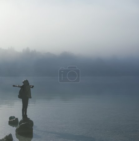 Girl tourist in thick fog on the lake enjoying life.