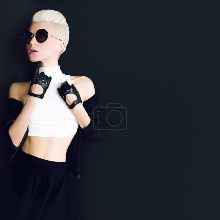 glamor model on black background in trendy gloves and sunglasses