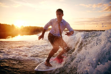 Man in wet clothes surfboarding