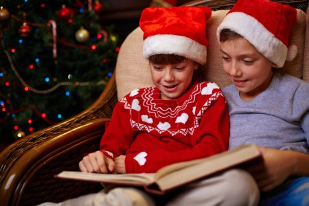 Children in Santa caps reading book