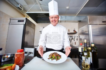 Male chef serving salad on plate